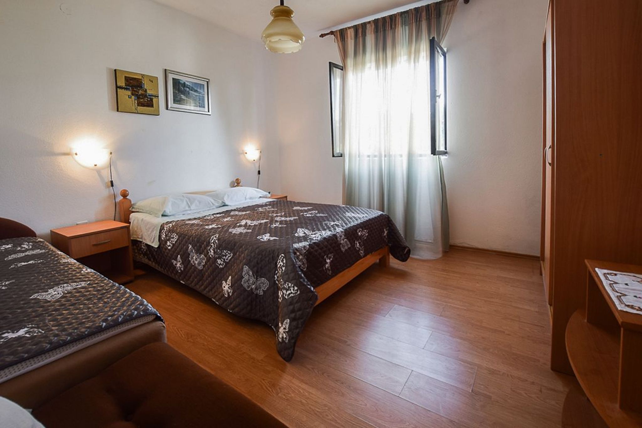 A bedroom with a bed, bedside tables, a wardrobe, and a window with curtains.