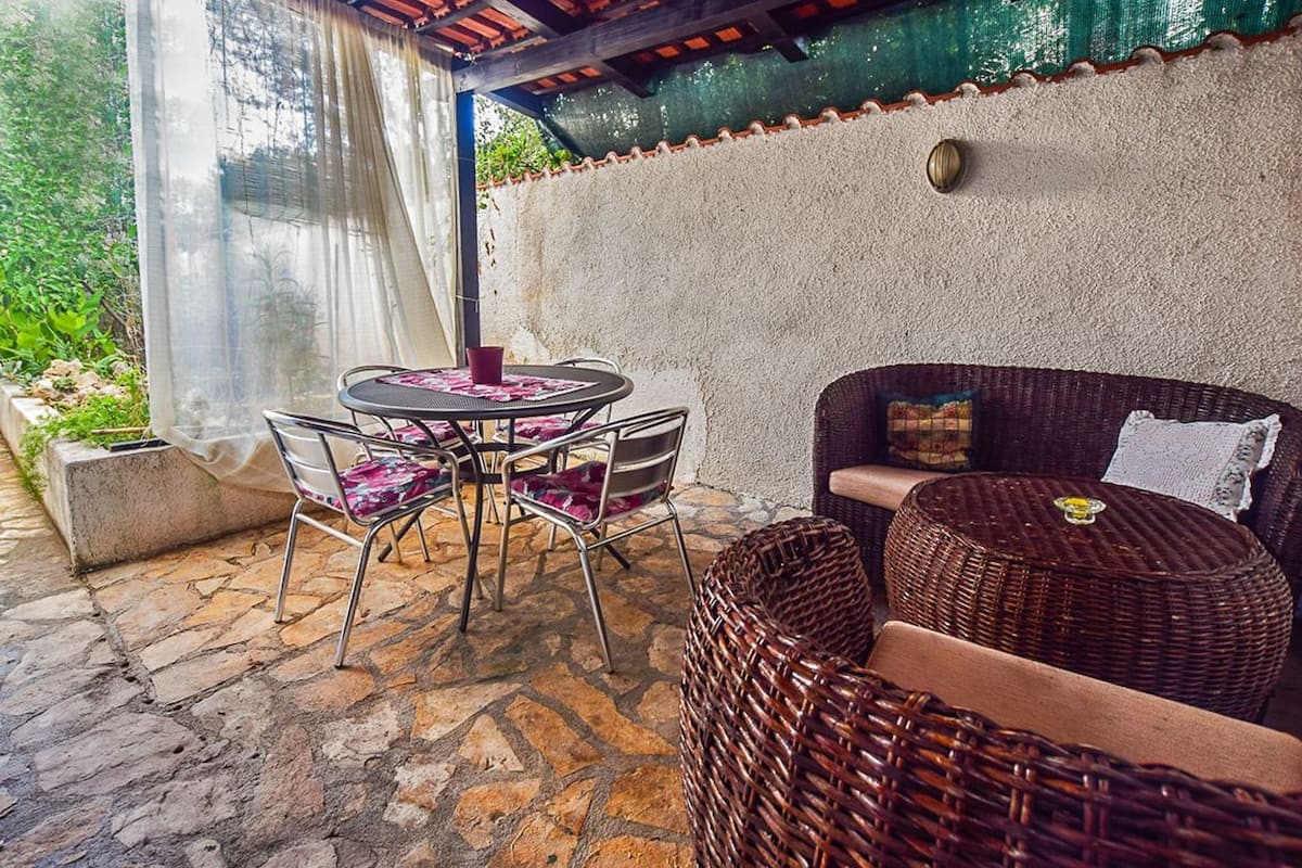 A patio area with a round table and chairs, a wicker sofa, and a cushioned bench.