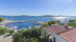 Un port de plaisance avec des bateaux amarrés, un ciel dégagé et une côte lointaine.