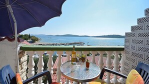 Un balcon avec une table, des chaises et un parasol bleu.