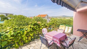 Un patio con mesa y sillas, vista a un viñedo y un edificio al fondo.