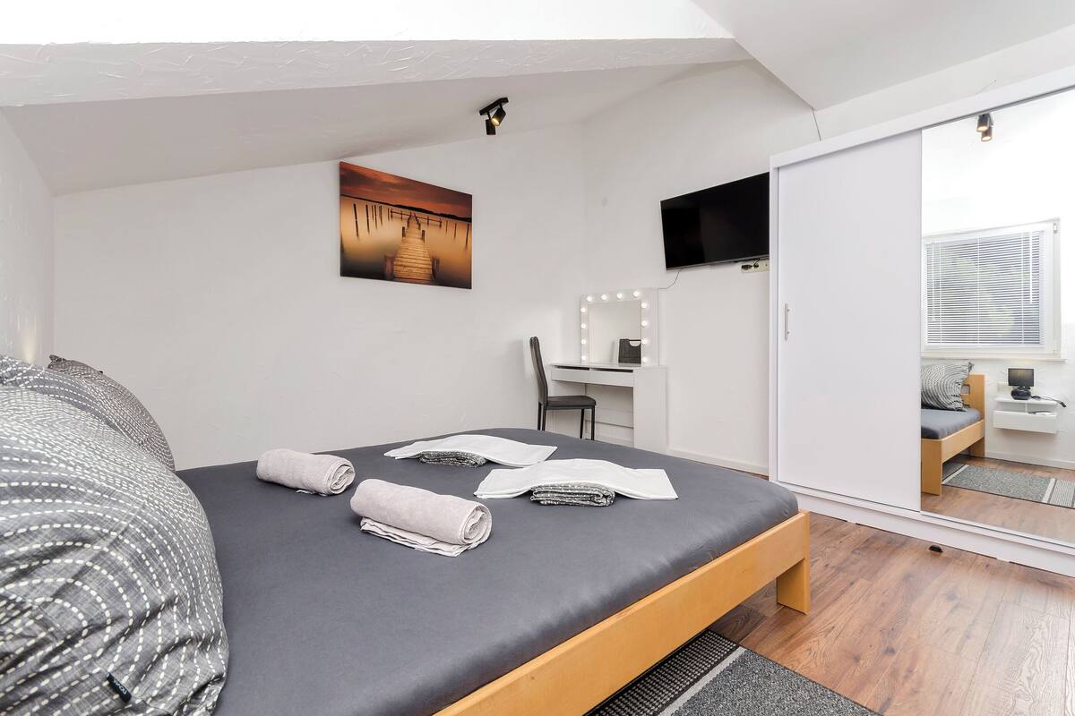 Un dormitorio moderno con cama, escritorio y espejo.