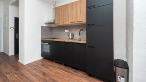 Moderni keittiö, jossa on mustat kaapit, puinen työtaso ja ruostumattomasta teräksestä valmistettu pesuallas.