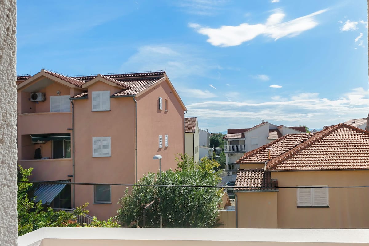 Un edificio residencial con tejado de tejas, varios balcones y cielo despejado.