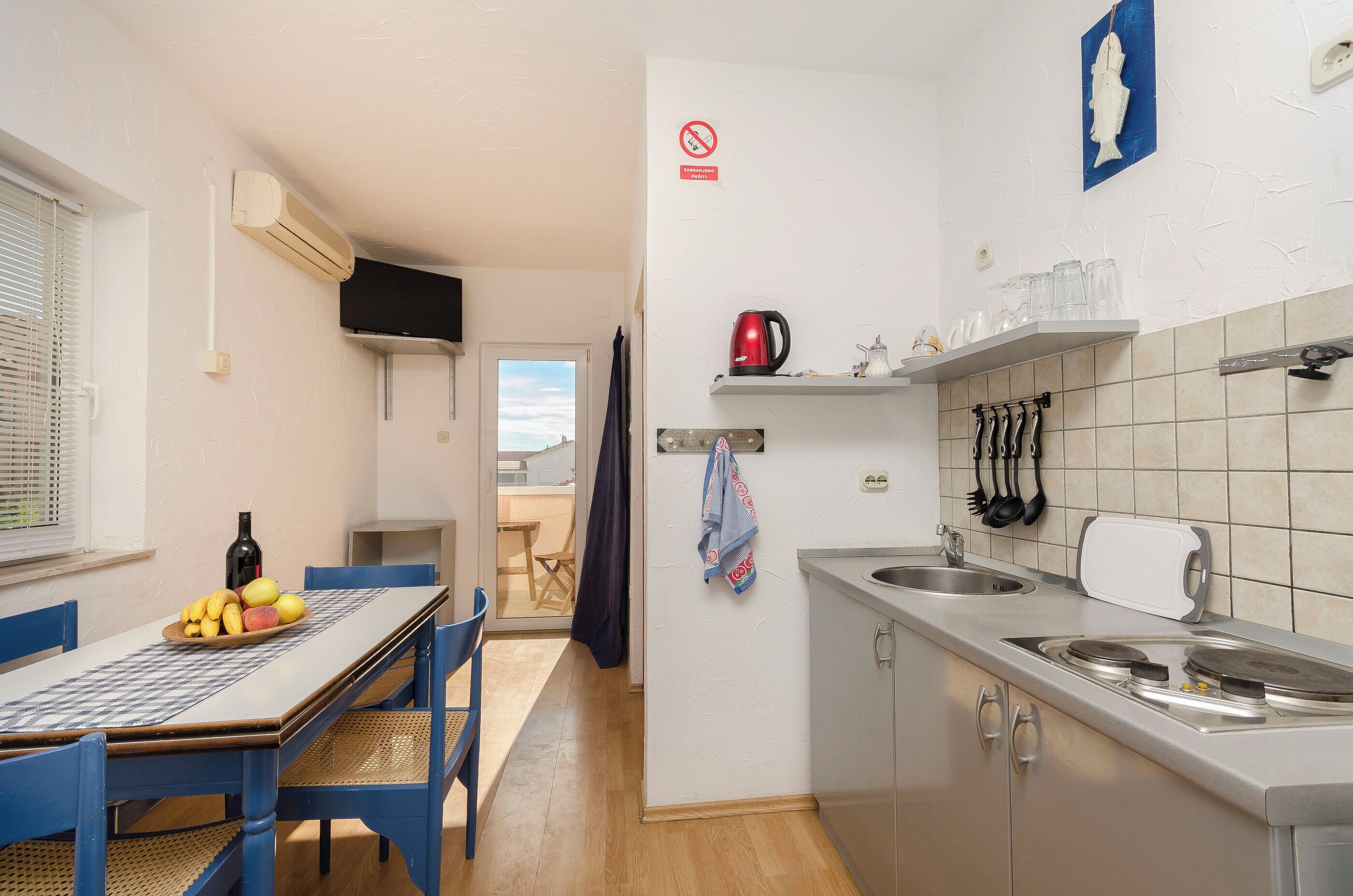 Une cuisine compacte comprenant un coin repas, une cuisinière encastrée et un petit évier.