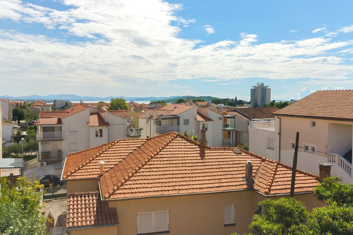 Zona residencial con techos de tejas de terracota, balcones y una vista despejada de montañas distantes.