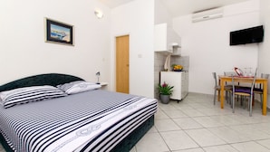 A bedroom with a bed, bedside table, and a small desk with a chair. - Apartments Kirigin (Supetar)
