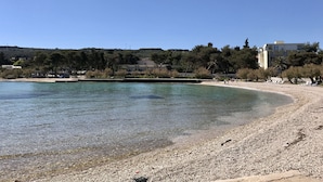 A beach with clear water, pebbles, and a few people. - Apartments Kirigin (Supetar)