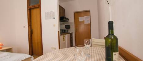 A hotel room with a checkered tablecloth, a bottle of wine, and two wine glasses.