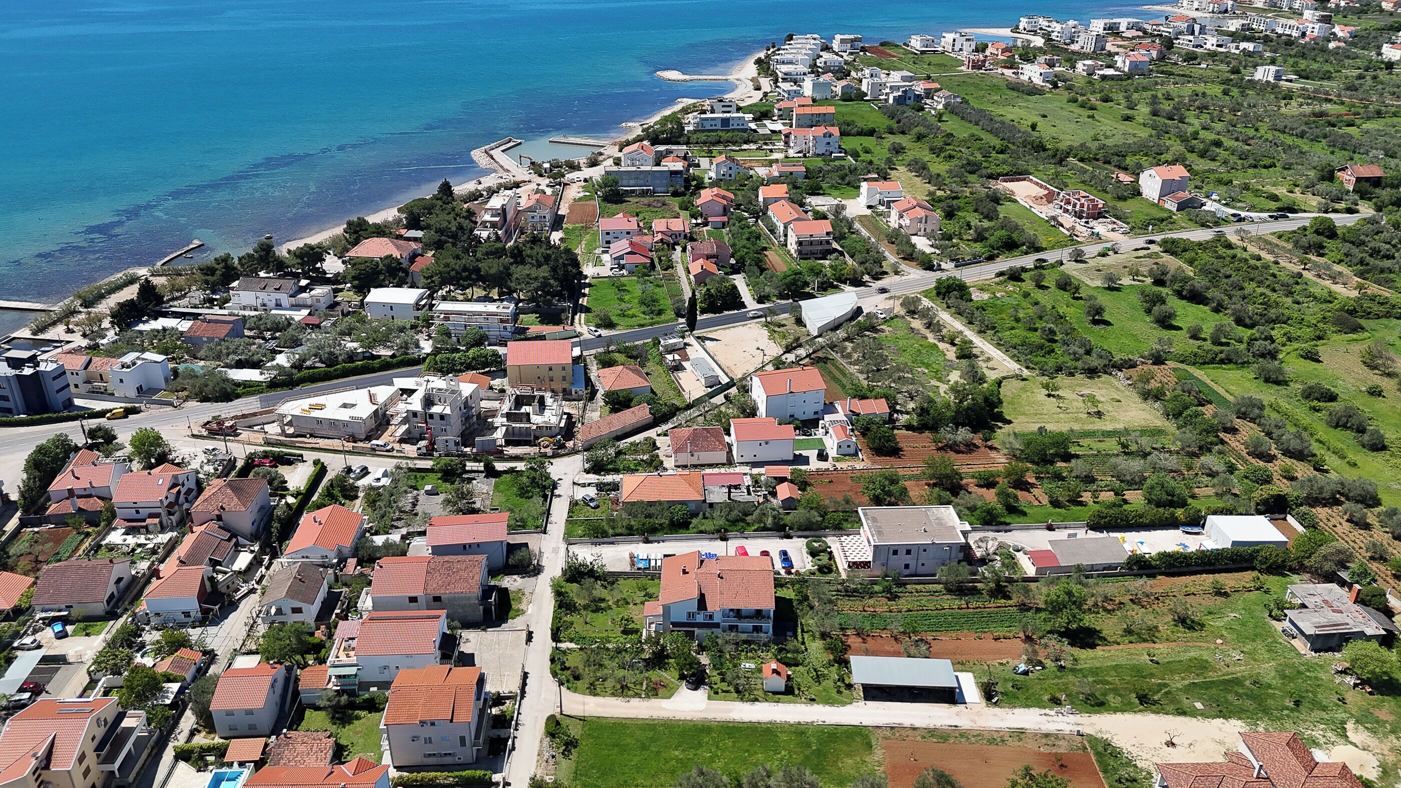 Vista aérea de una zona residencial costera con casas, carreteras y una playa.