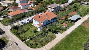 An aerial view of a residential area with houses, a road, and a vineyard. - Apartments Verica (Sukosan)