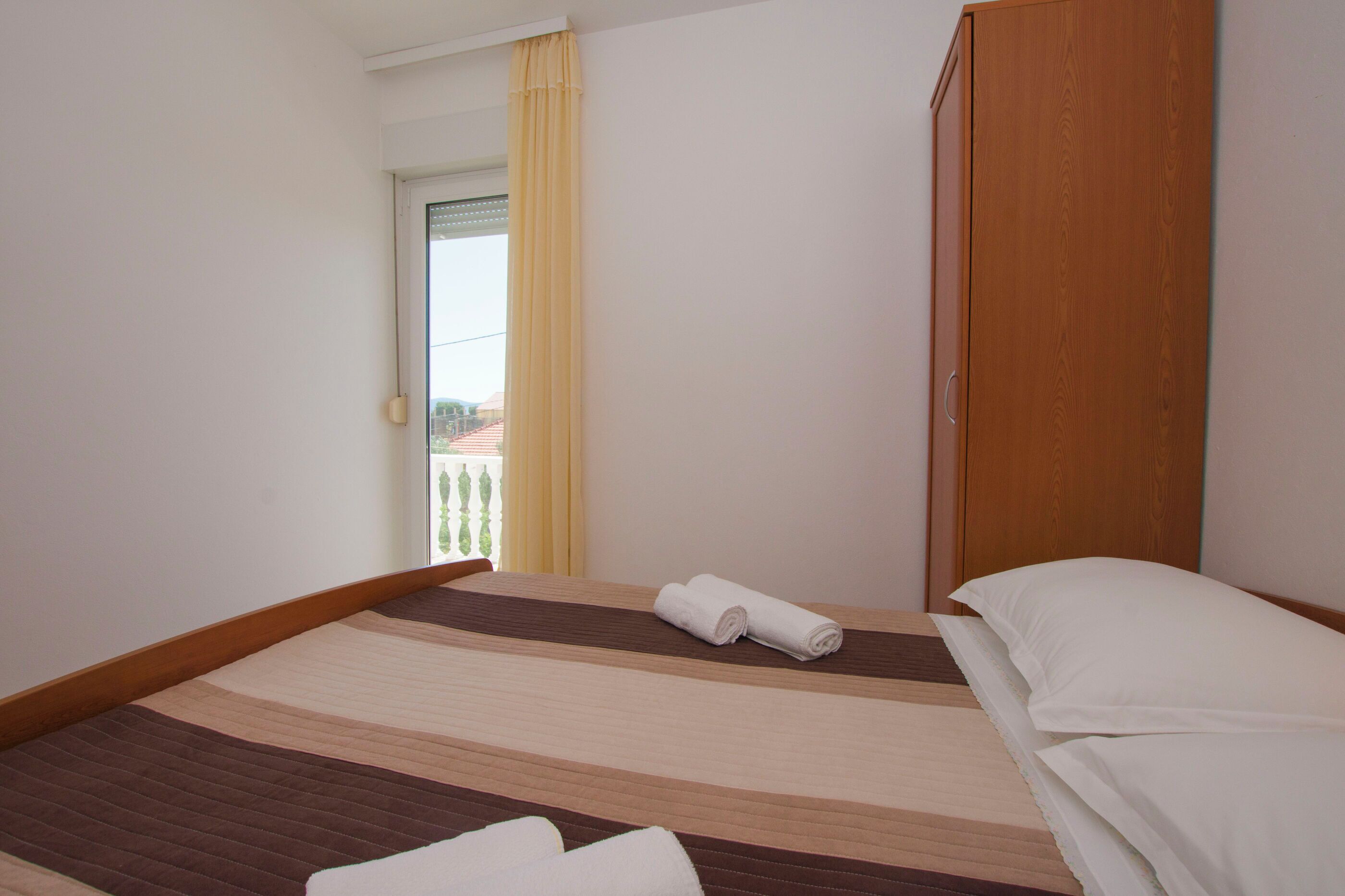 Ein Hotelzimmer mit einem Bett, einem Holzschrank und Blick auf einen Balkon.