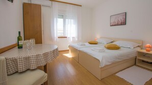 A bedroom with a bed, bedside table, and a small table with a bottle and glasses. - Apartments Verica (Sukosan)