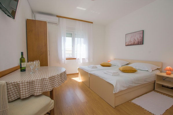 A bedroom with a bed, bedside table, and a small table with a bottle and glasses. - Apartments Verica (Sukosan)
