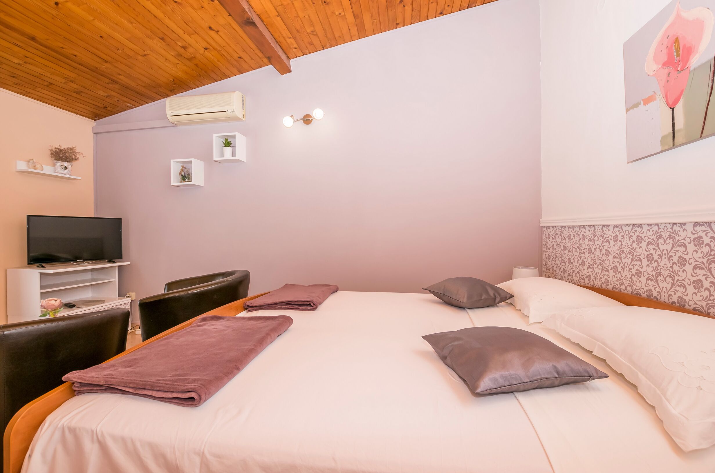 Un dormitorio con cama, televisor, escritorio y silla.