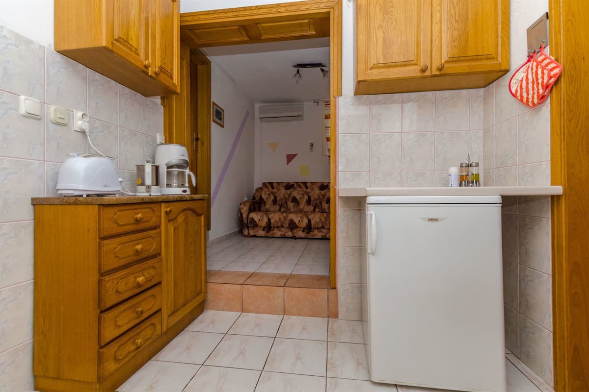 A compact kitchen with wooden cabinets, a white refrigerator, and a coffee maker.