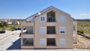 A multi-story building with balconies, a garage, and a clear view of the surrounding landscape. - Apartment Sunset (Vodice)
