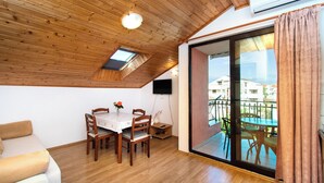 Un coin repas avec un plafond en bois, une table entourée de chaises et une vue sur un balcon aménagé avec du mobilier d’extérieur.