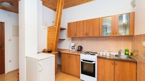 Une cuisine de taille réduite, avec des meubles en bois, un réfrigérateur blanc, une cuisinière et une machine à café.