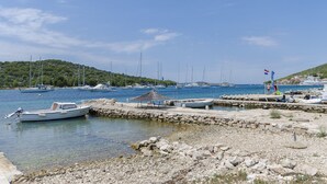 Un port de plaisance avec des bateaux amarrés, une côte rocheuse et une petite cabane.