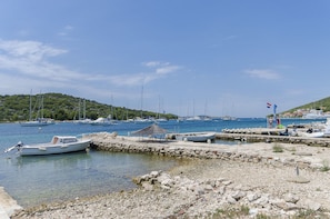 Ein Yachthafen mit vertäuten Booten, eine felsige Küstenlinie und ein klarer, blauer Himmel.