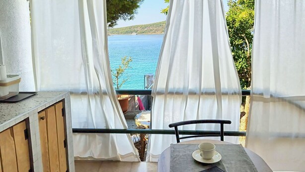 Une pièce avec vue sur une étendue d’eau, une table avec une tasse et un clavier, et une chaise.