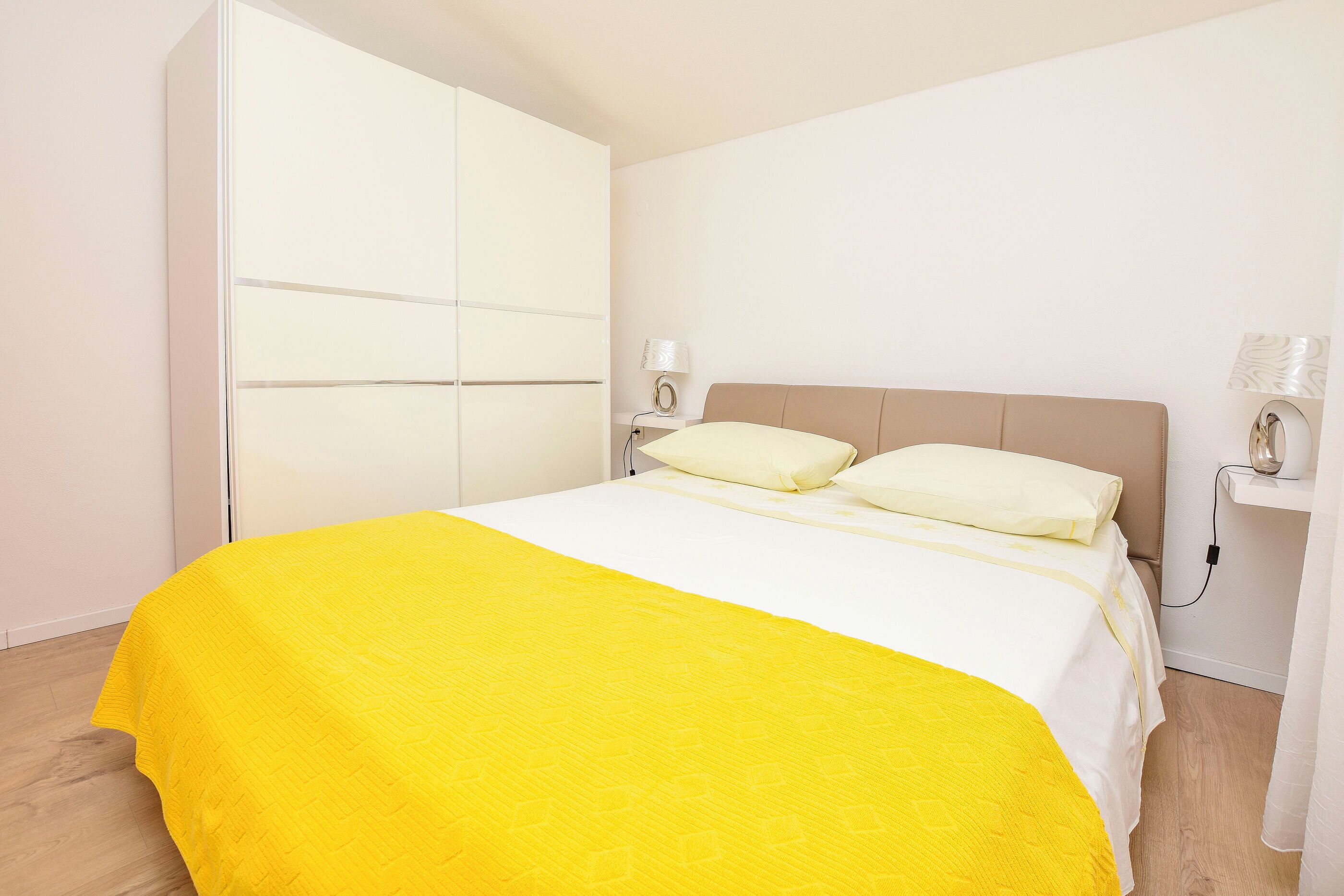 Une chambre à coucher avec un lit, une armoire, une table de chevet et une lampe.