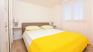 Een slaapkamer met een bed, twee bedlampen, een raam met gordijnen en een houten vloer.