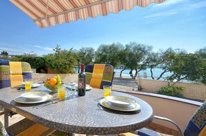 An outdoor dining area with a table set for two, featuring patterned chairs and a view of the sea. - Apartment Srima (Srima)