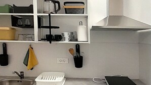 Een moderne keuken met grijze kastjes, een inbouwoven en een roestvrijstalen afzuigkap.