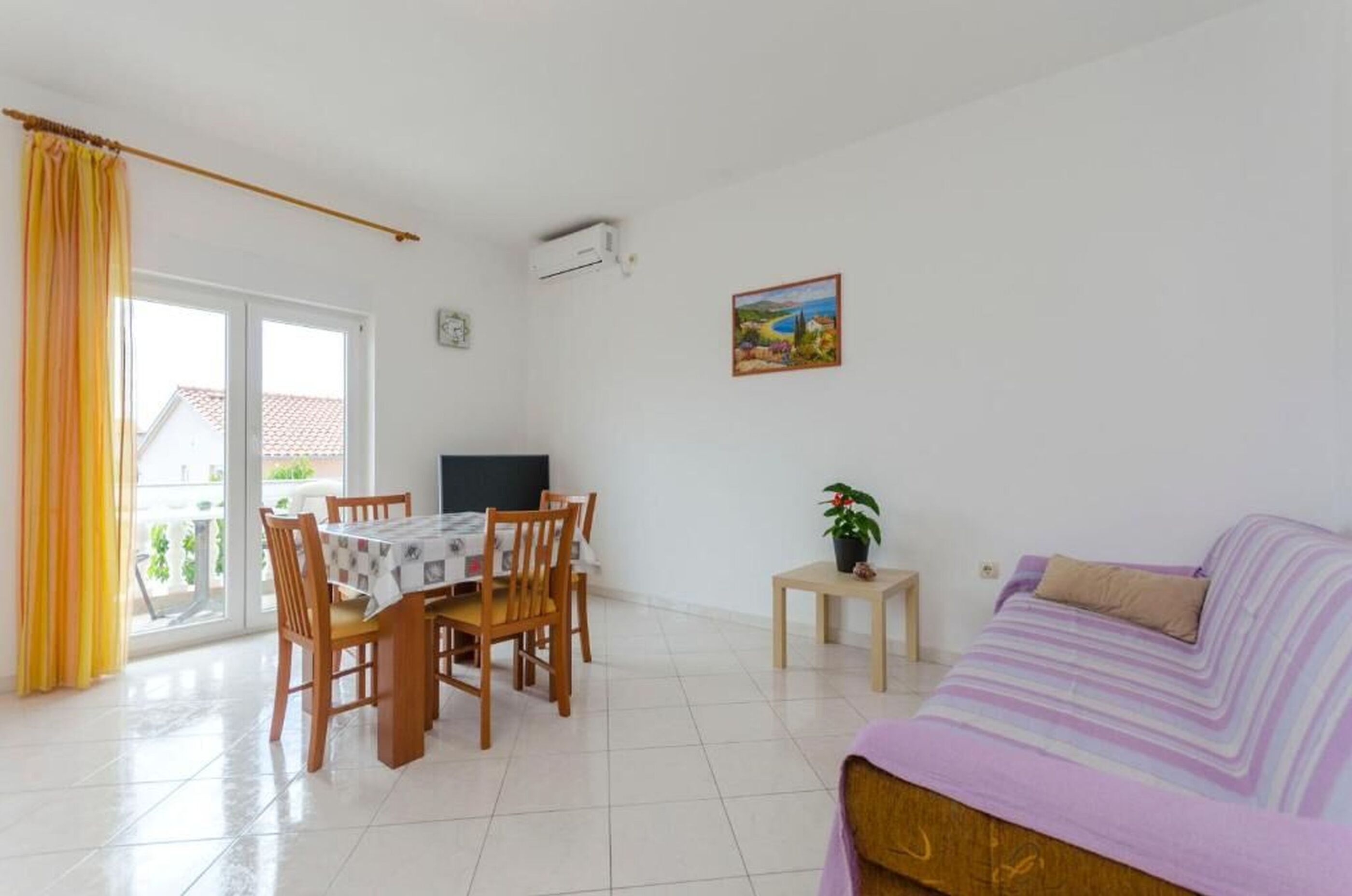 Un salón luminoso con comedor, un sofá y una mesita con una planta.