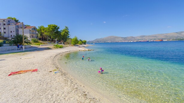 A beach with clear water, a few people, and buildings in the background. - Apartment Piveta (Okrug Gornji)