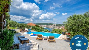 A private pool with lounge chairs and a view of a town. - Apartment Piveta (Okrug Gornji)