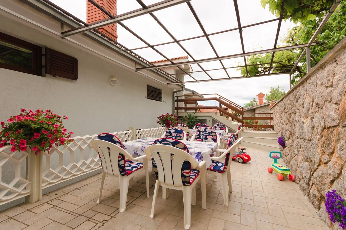 Eine Außenpatio mit Tisch und Stühlen, ein Spielzeug-Fahrzeug für Kinder und eine Steinmauer.