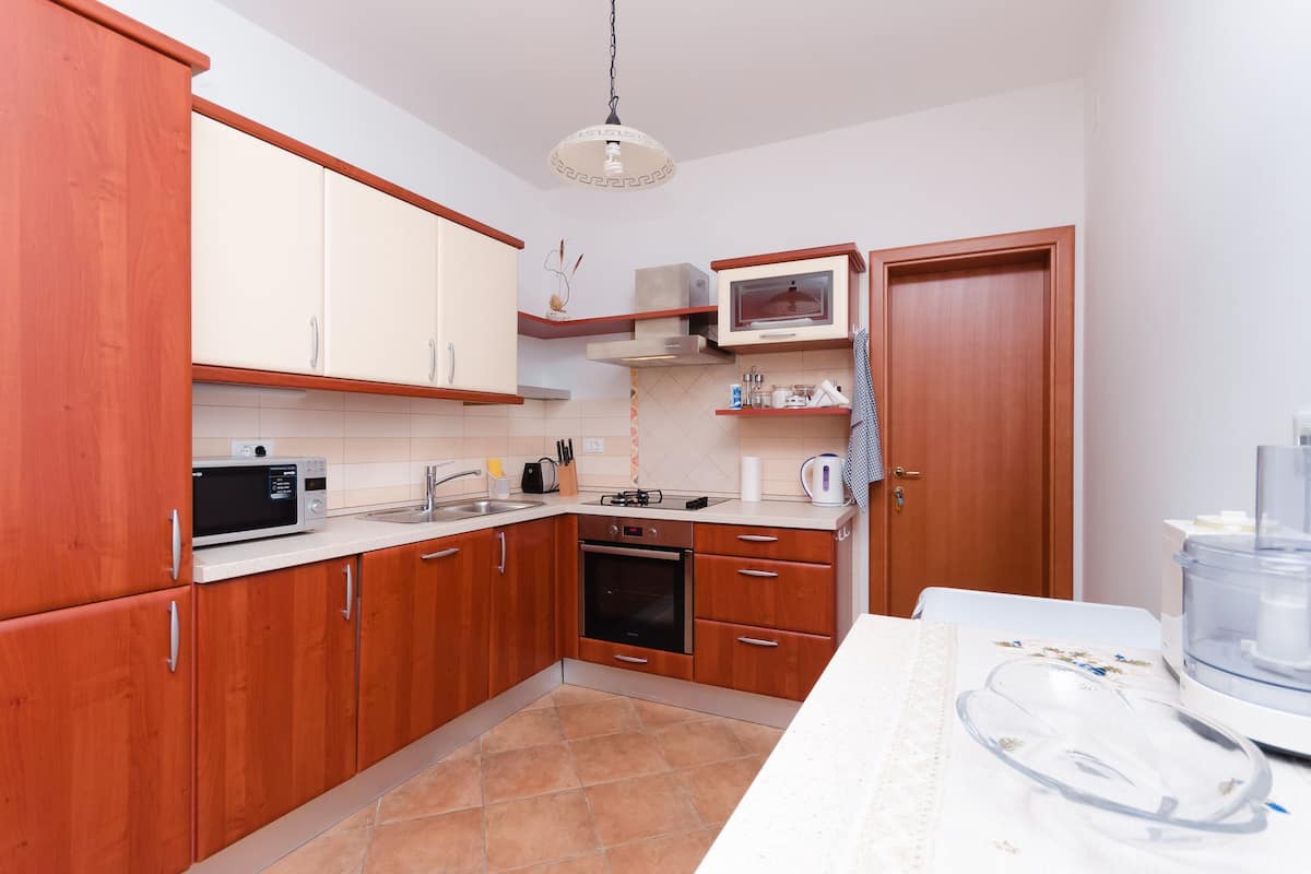 Eine kleine Küche mit Holzausstattung, einer Mikrowelle, einem Backofen und einem Spülbecken.