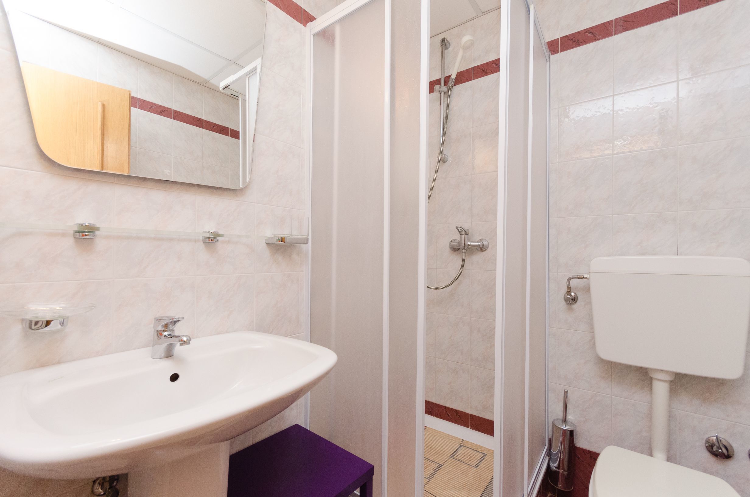 A bathroom with a sink, mirror, shower, and toilet.