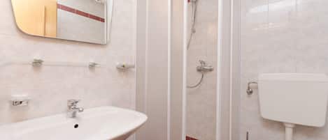 A bathroom with a sink, mirror, shower, and toilet.