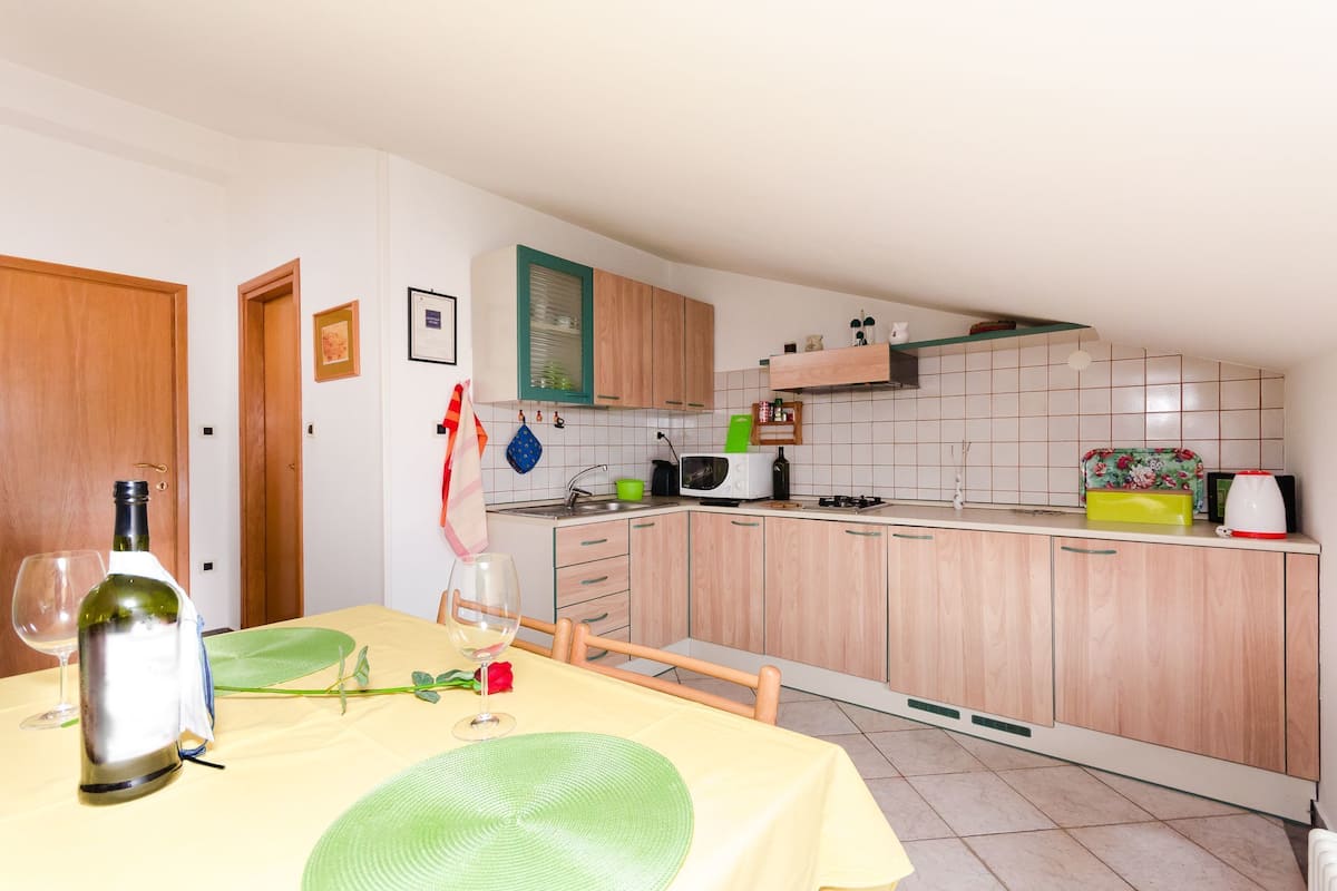 Eine kleine Küche mit Holzschränken, einer Mikrowelle und einer kompakten Arbeitsfläche.