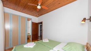A bedroom with two beds, wooden ceiling, and a ceiling fan. - Apartment Lidija (Tisno)