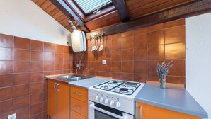 A kitchen with brown tiles, a gas stove, and a sink. - Apartment Lidija (Tisno)