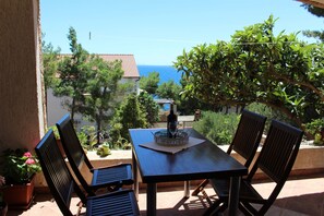 Une terrasse avec une table et des chaises, offrant une vue sur la mer et les bâtiments.