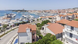 A marina with numerous boats docked, surrounded by residential buildings with red-tiled roofs.