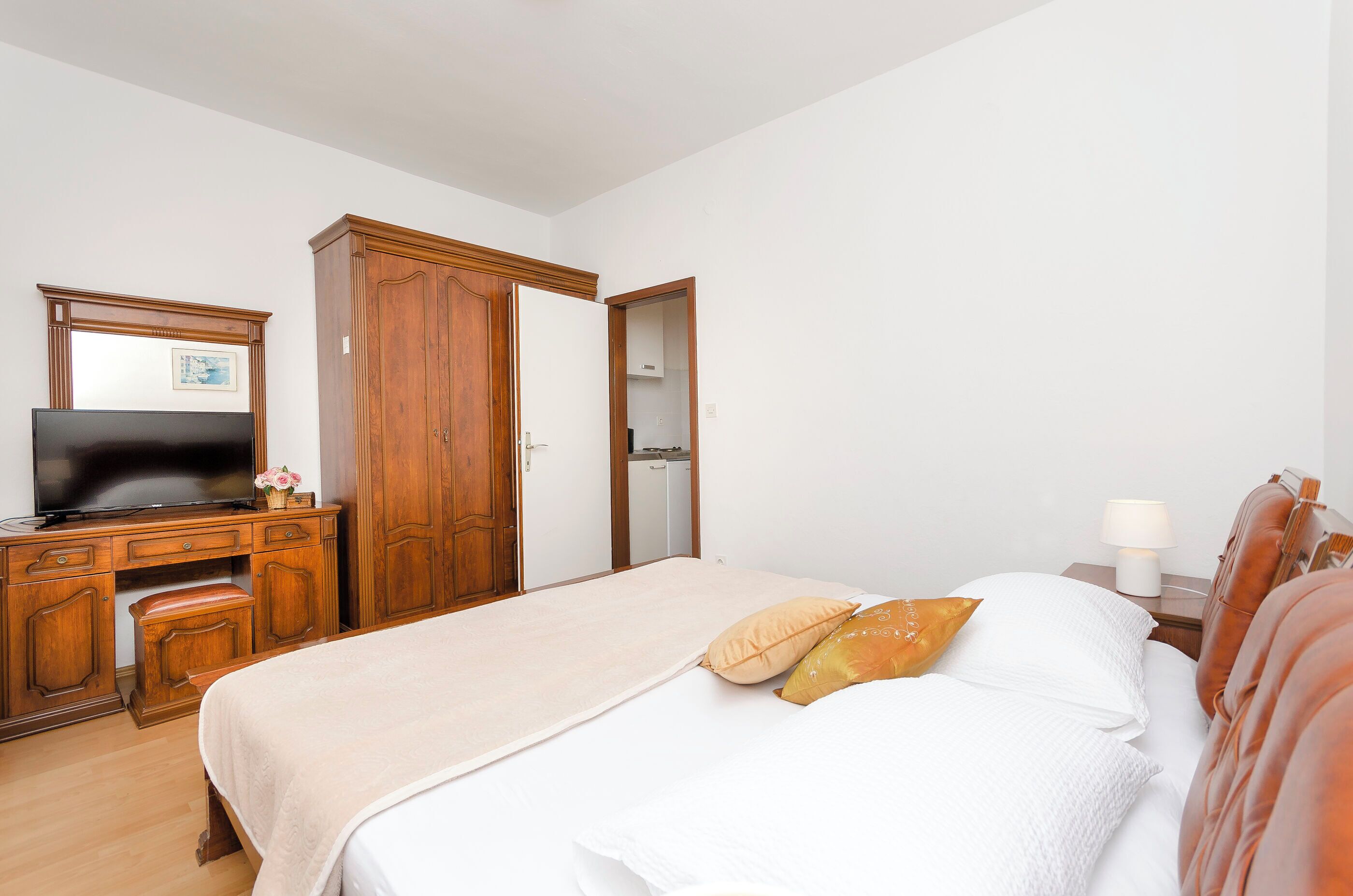 Une chambre d’hôtel avec un lit, une télévision, des meubles en bois et une table de chevet avec une lampe.