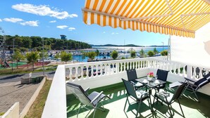 A balcony with a view of a marina and a distant cityscape.