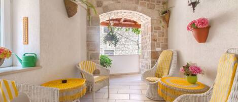A cozy patio area with wicker furniture, a stone archway, and hanging plants.