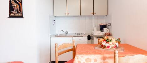 A compact kitchen with white cabinets, a sink, and a dining area with a table set for two.