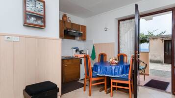 Une cuisine compacte avec des meubles en bois, un four à micro-ondes encastré et un petit coin repas comprenant une table et des chaises.