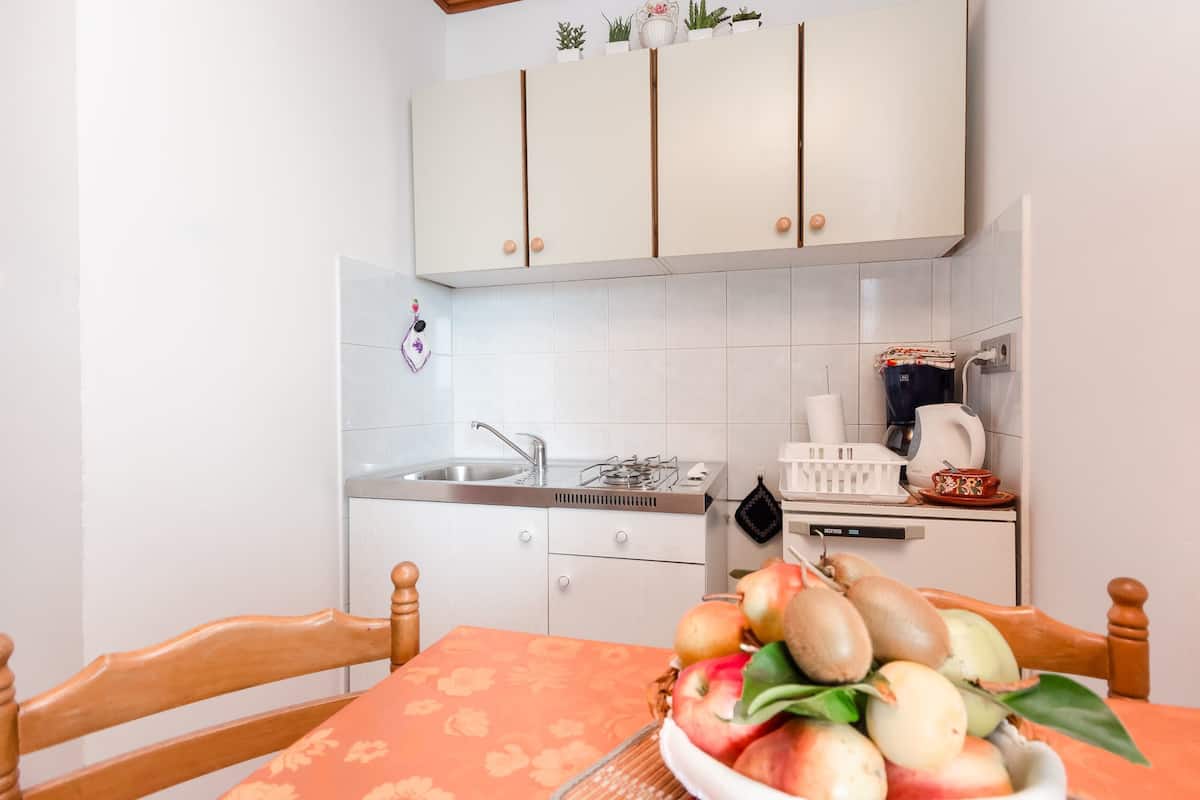 Una cocina con armarios blancos, un fregadero, una estufa y una zona de comedor con mesa y sillas.