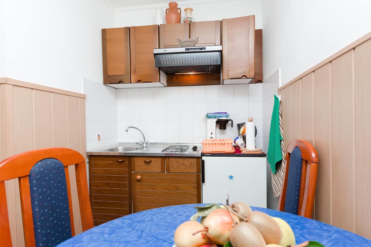 Una cocina compacta con armarios de madera, estufa integrada y un refrigerador pequeño.