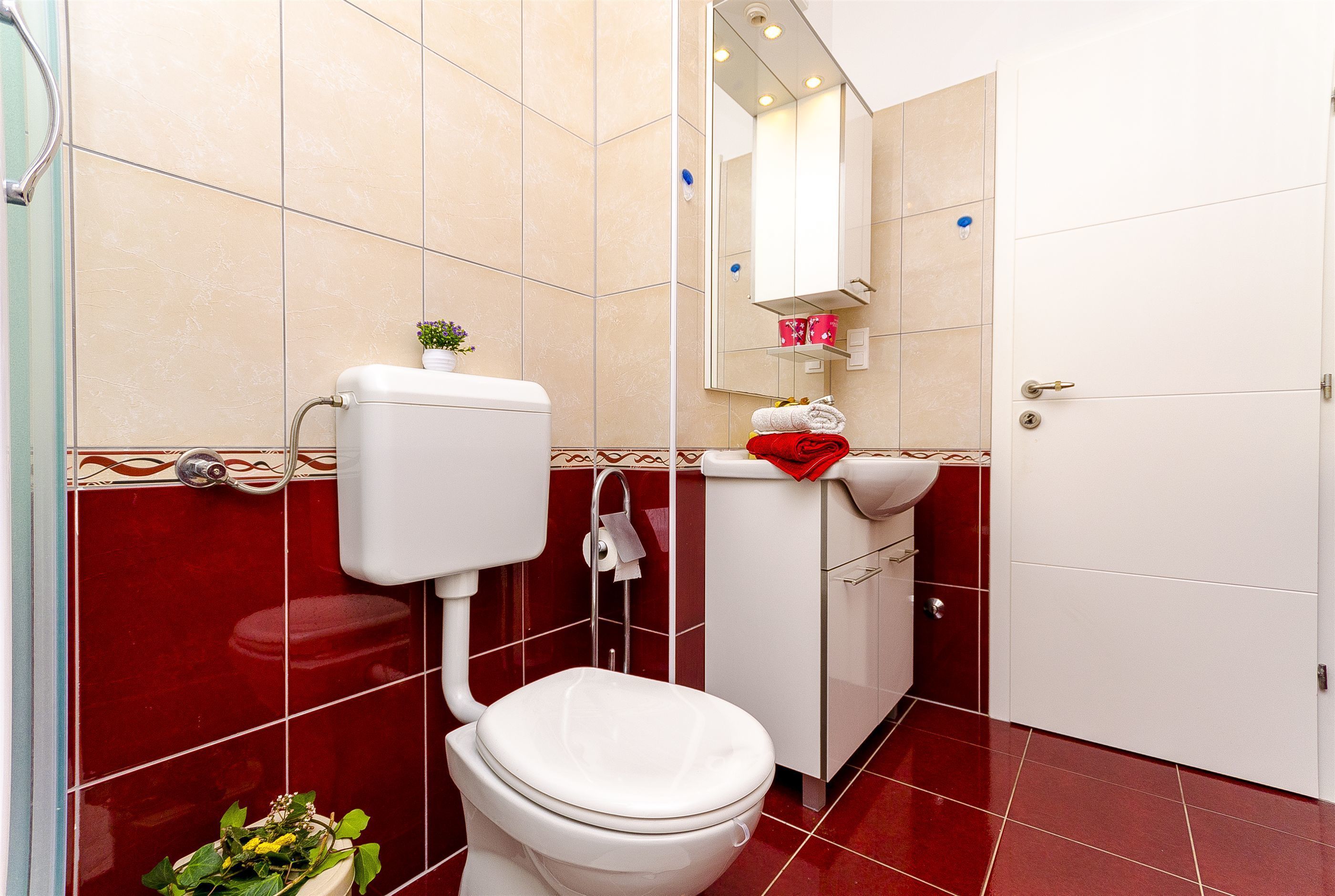 Une salle de bain comprenant des toilettes, un lavabo, un miroir et un espace douche.